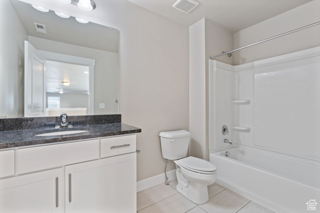Full bathroom with tile flooring, large vanity, toilet, and washtub / shower combination