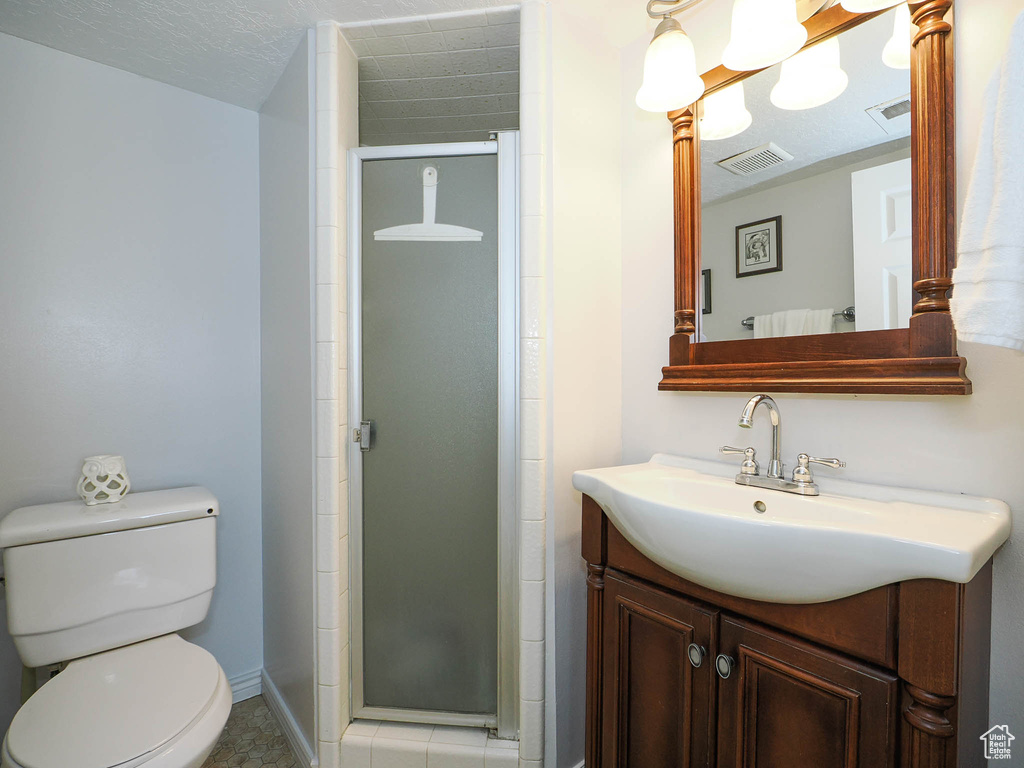 Bathroom with walk in shower, a textured ceiling, toilet, and vanity
