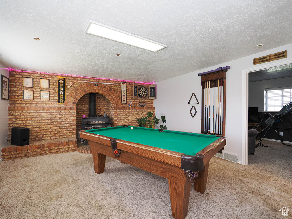Recreation room with a wood stove, light carpet, a textured ceiling, and billiards