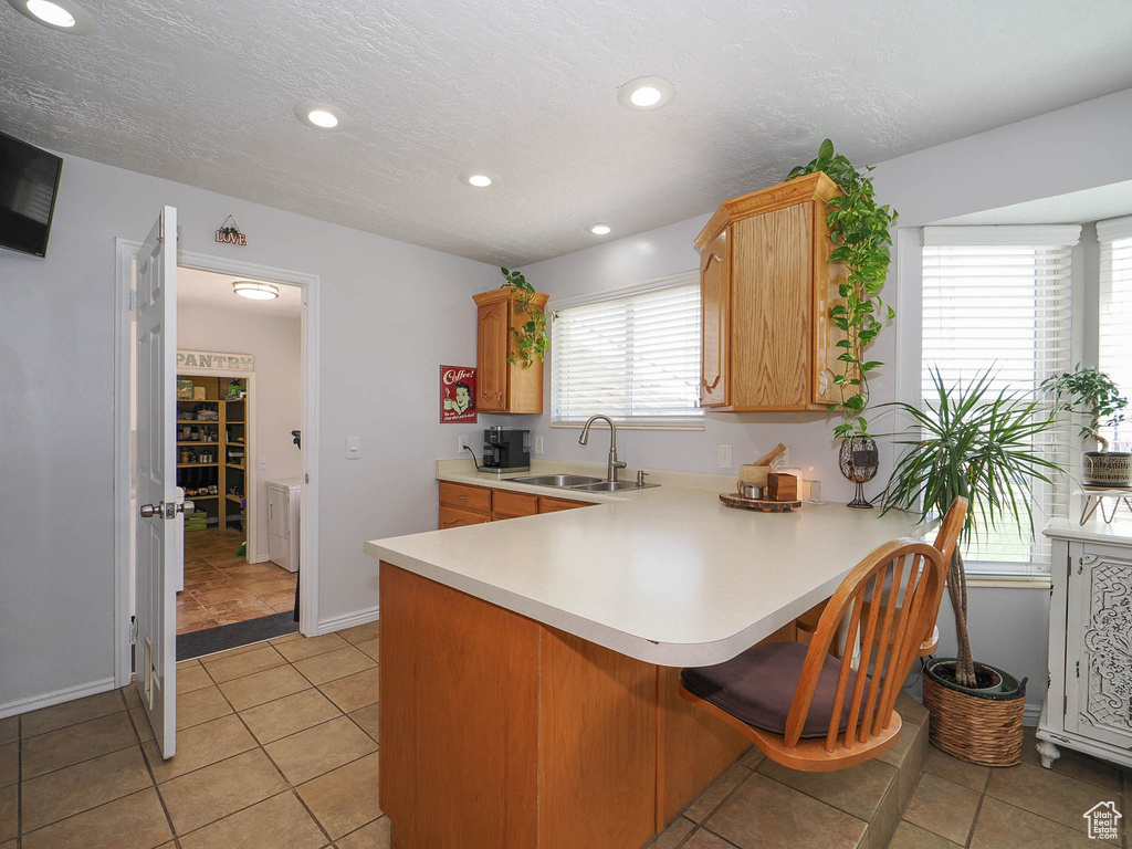 Kitchen featuring a breakfast bar, sink, light tile floors, and kitchen peninsula