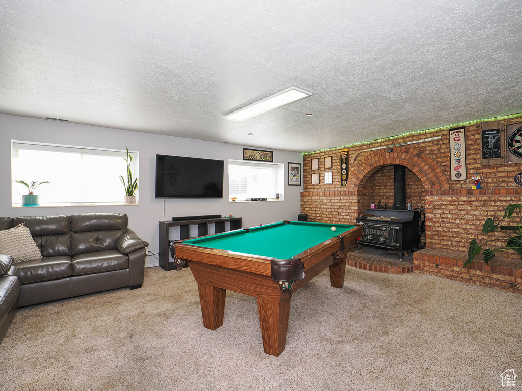Playroom featuring a wood stove, a textured ceiling, billiards, and plenty of natural light