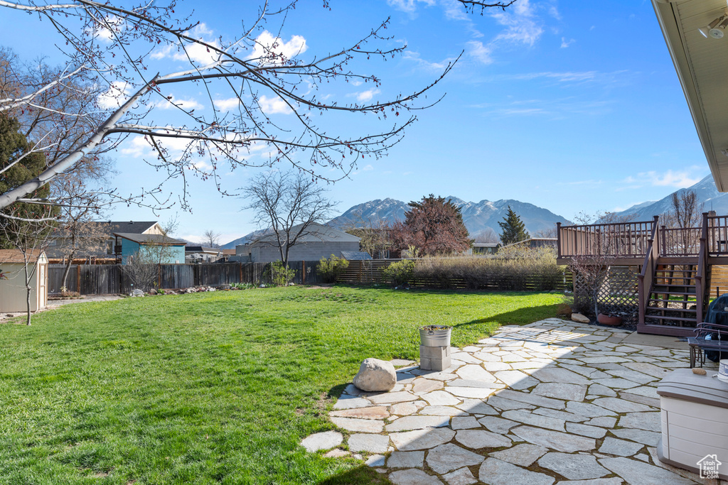 View of yard featuring a deck with mountain view and a patio