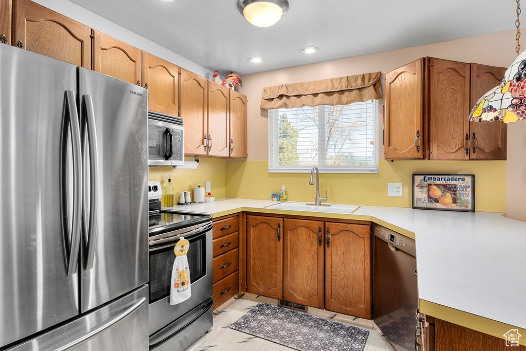 Kitchen with appliances with stainless steel finishes, decorative light fixtures, light tile floors, and sink