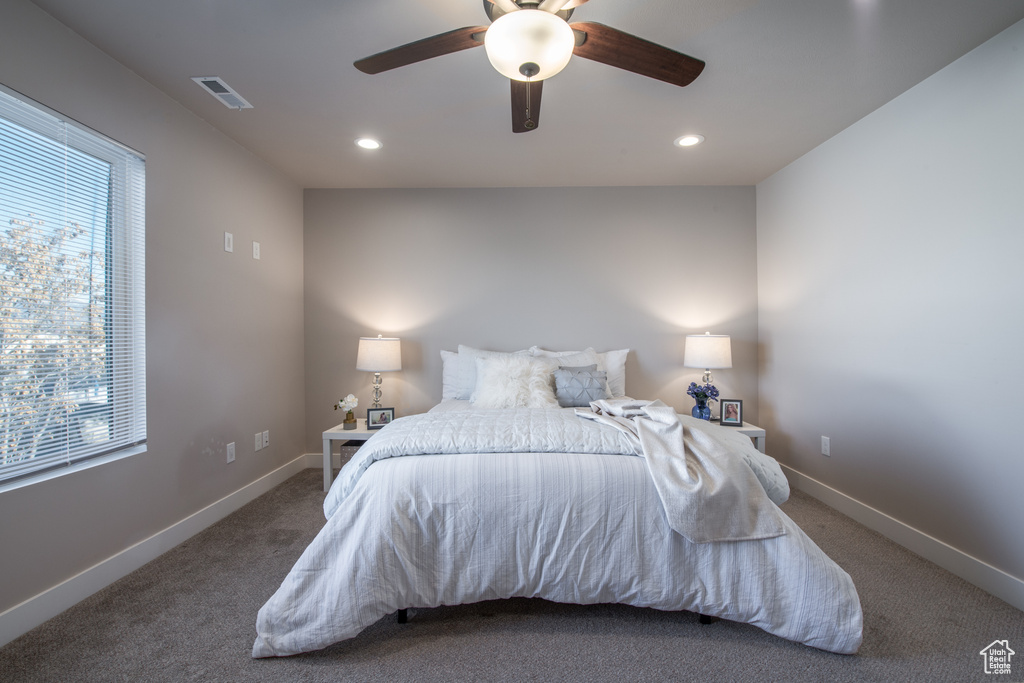Bedroom featuring ceiling fan, dark colored carpet, and multiple windows
