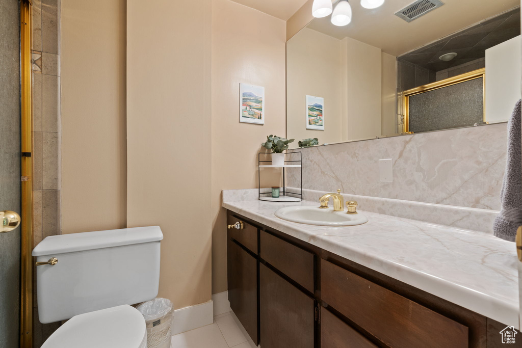 Bathroom featuring tile flooring, toilet, and vanity with extensive cabinet space