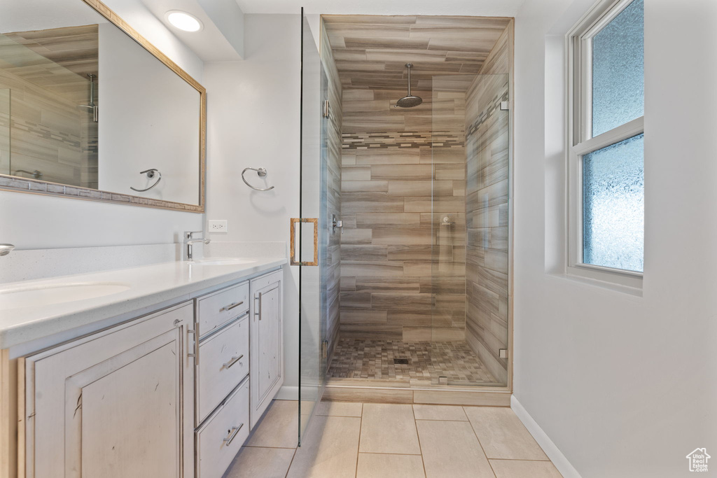 Bathroom featuring tile floors, double sink vanity, and an enclosed shower