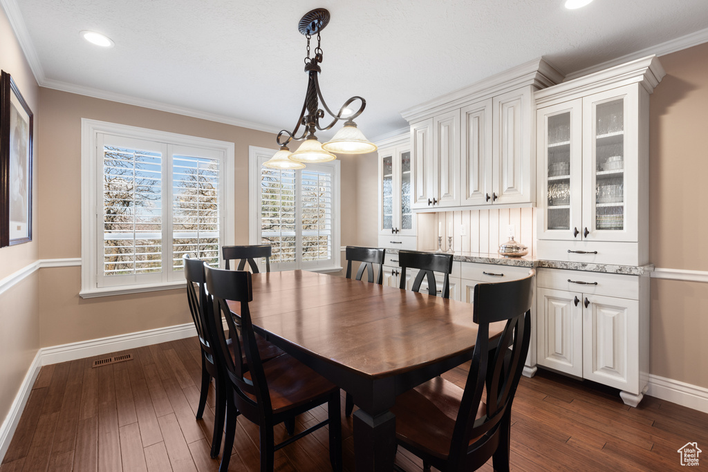 Dining space featuring ornamental molding and dark hardwood / wood-style flooring