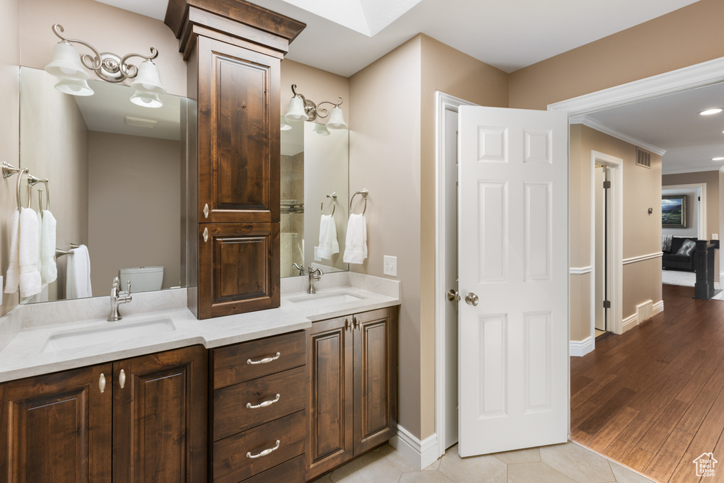 Bathroom featuring ornamental molding, toilet, tile floors, and double sink vanity