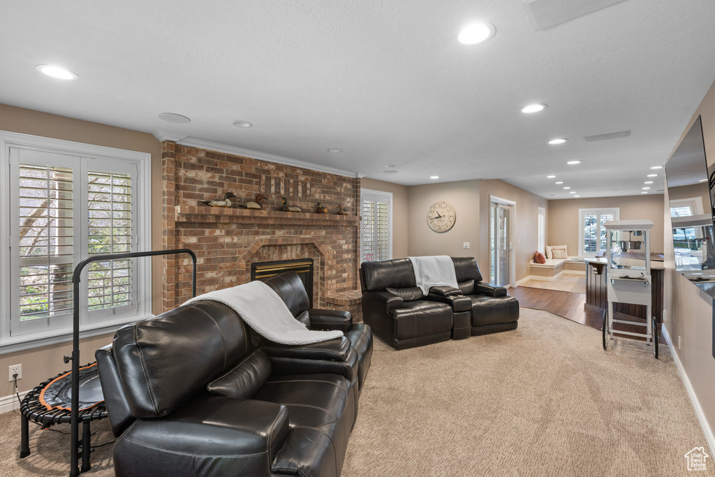 Living room featuring a brick fireplace, light carpet, and plenty of natural light
