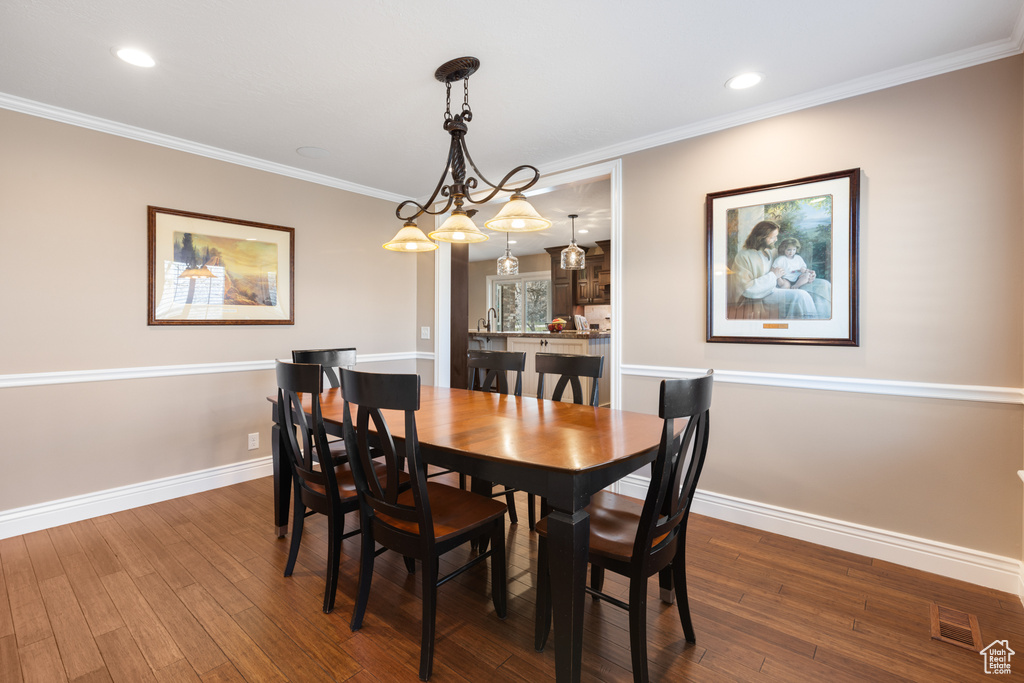 Dining area with ornamental molding and dark hardwood / wood-style flooring