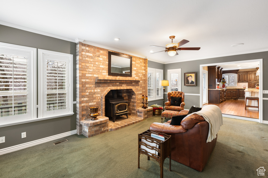 Living room featuring crown molding, brick wall, dark colored carpet, and a wealth of natural light