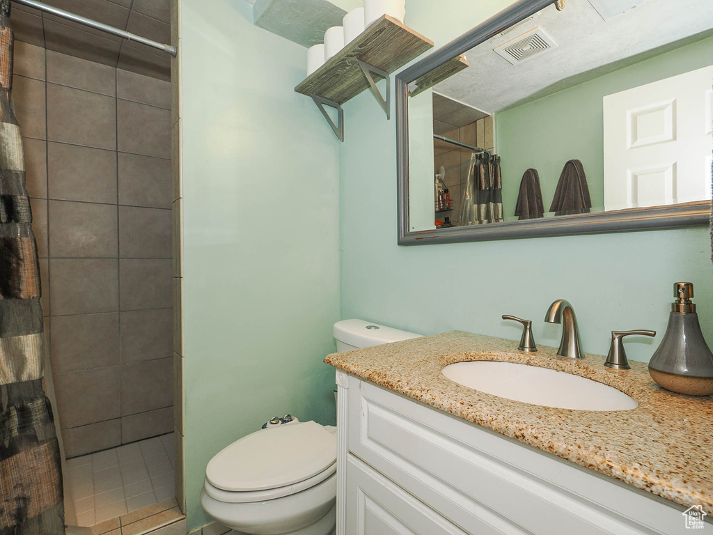 Bathroom featuring a shower with shower curtain, toilet, and vanity with extensive cabinet space