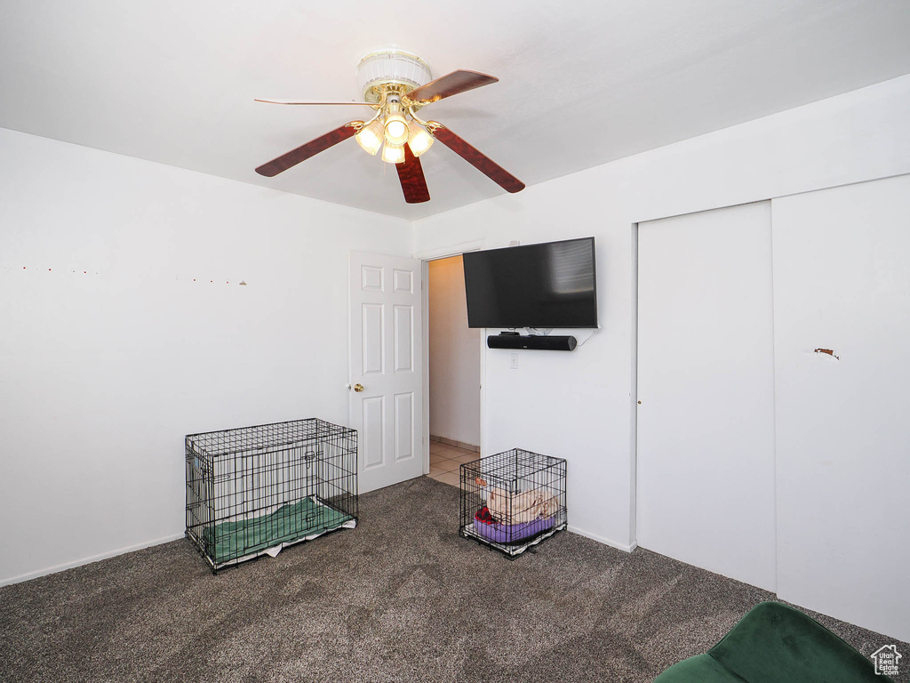 Interior space with ceiling fan, a closet, and dark carpet