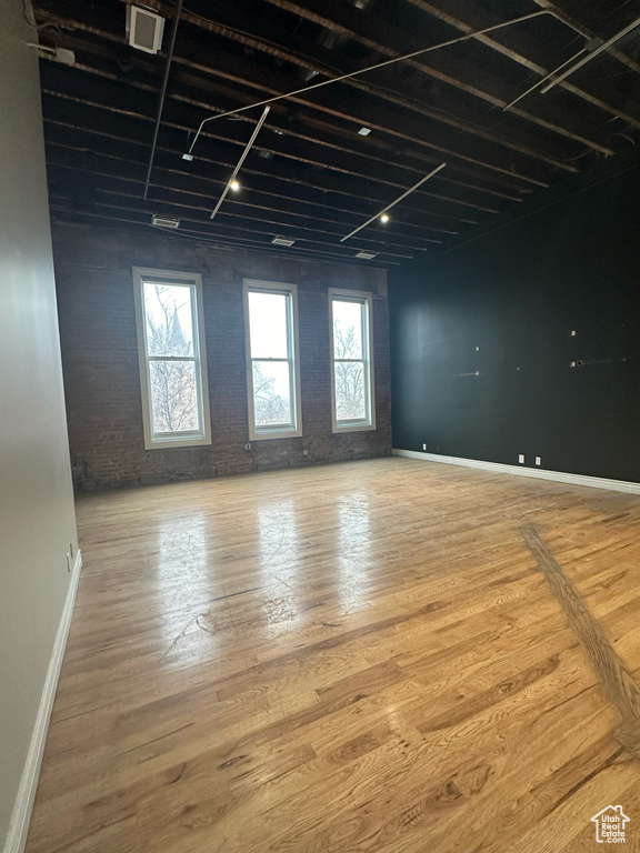 Unfurnished room with brick wall and light hardwood / wood-style flooring