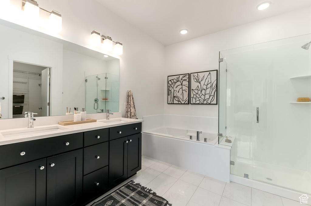 Bathroom featuring plus walk in shower, dual sinks, vanity with extensive cabinet space, and tile floors