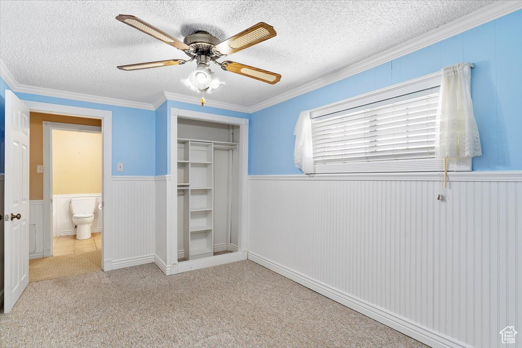 Unfurnished bedroom with ceiling fan, a textured ceiling, crown molding, and a closet