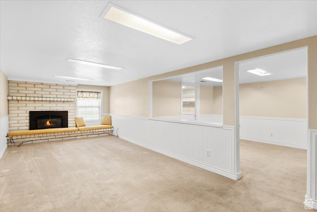 Basement featuring a textured ceiling, a fireplace, and light carpet