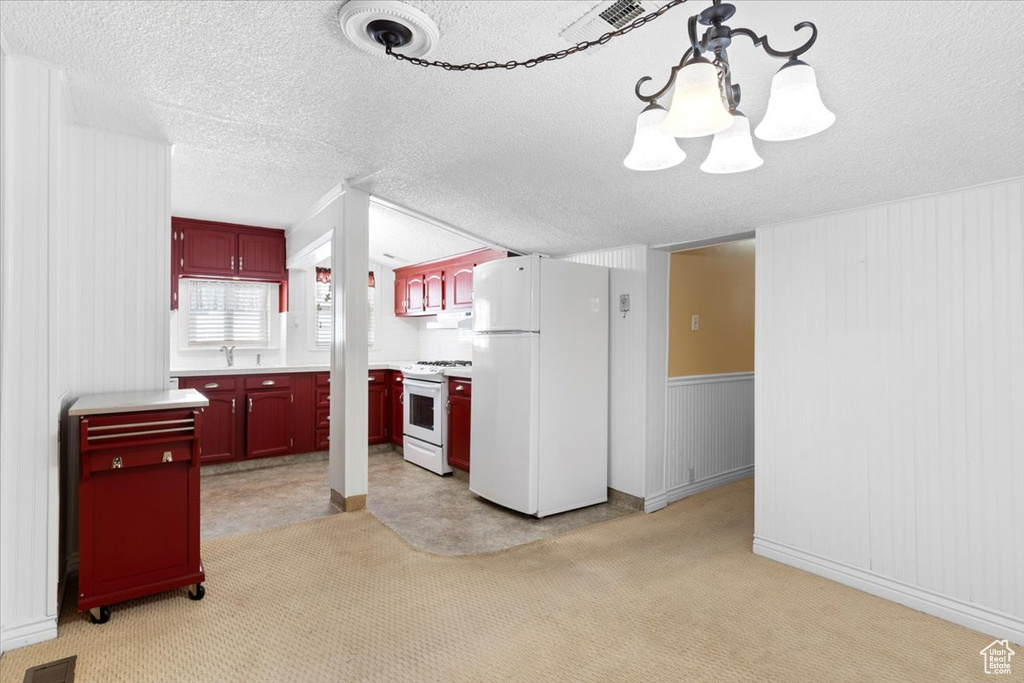 Kitchen featuring a chandelier, white appliances, a textured ceiling, and light colored carpet