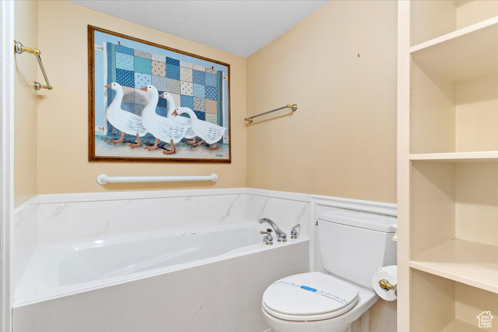 Bathroom featuring a tub, toilet, and a textured ceiling