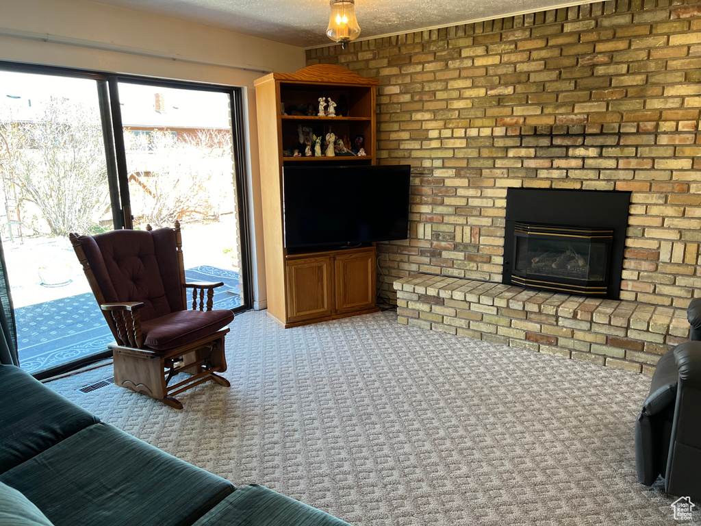 Carpeted living room featuring brick wall, a brick fireplace, and a textured ceiling