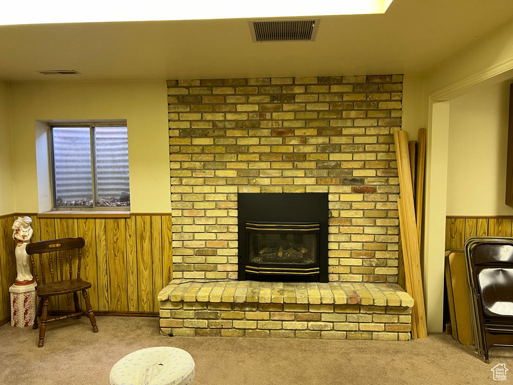 Living room featuring a brick fireplace, brick wall, and light colored carpet