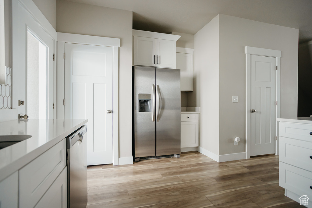 Kitchen featuring appliances with stainless steel finishes, white cabinetry, and light hardwood / wood-style flooring