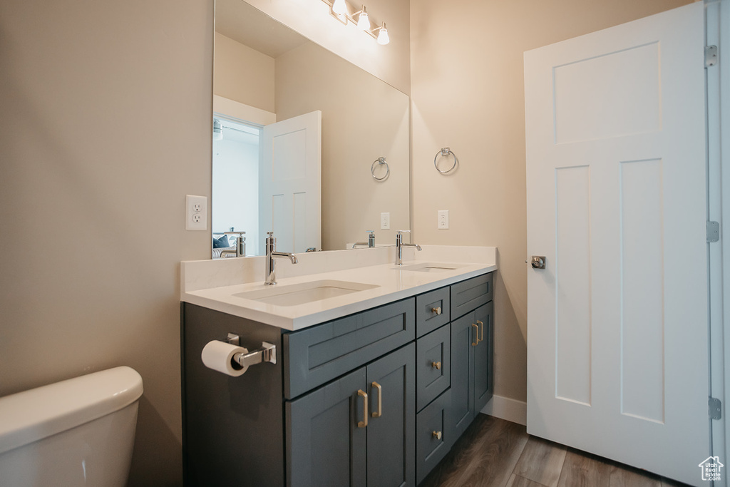 Bathroom with toilet, hardwood / wood-style floors, and dual vanity