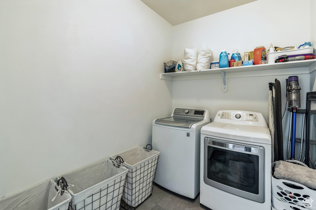 Clothes washing area featuring tile floors and separate washer and dryer