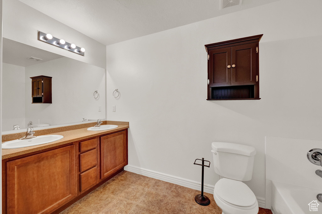Bathroom featuring double sink, tile floors, oversized vanity, and toilet