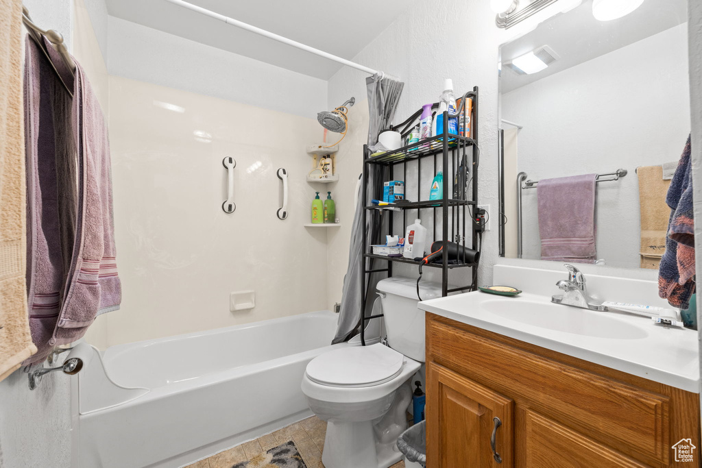 Full bathroom featuring toilet, tile floors, vanity, and shower / bath combo