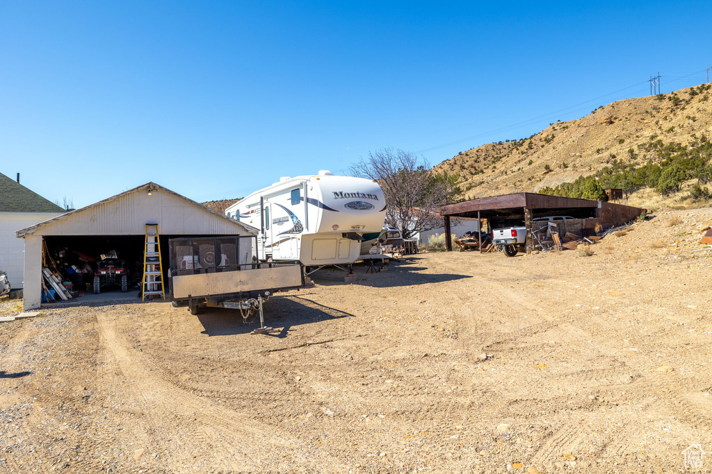 View of yard with a mountain view, a carport, an outdoor structure, and a garage