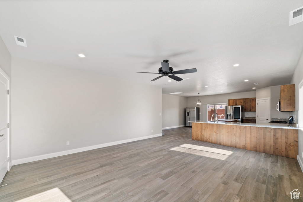 Kitchen with ceiling fan, light wood-type flooring, and stainless steel fridge with ice dispenser