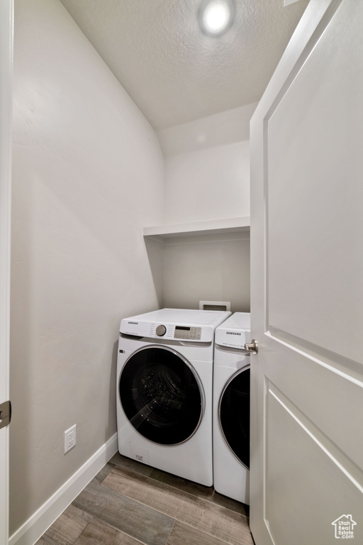 Clothes washing area featuring washing machine and clothes dryer, a textured ceiling, dark hardwood / wood-style floors, and hookup for a washing machine