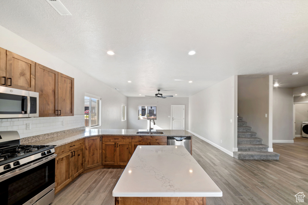 Kitchen with appliances with stainless steel finishes, ceiling fan, light hardwood / wood-style flooring, and sink