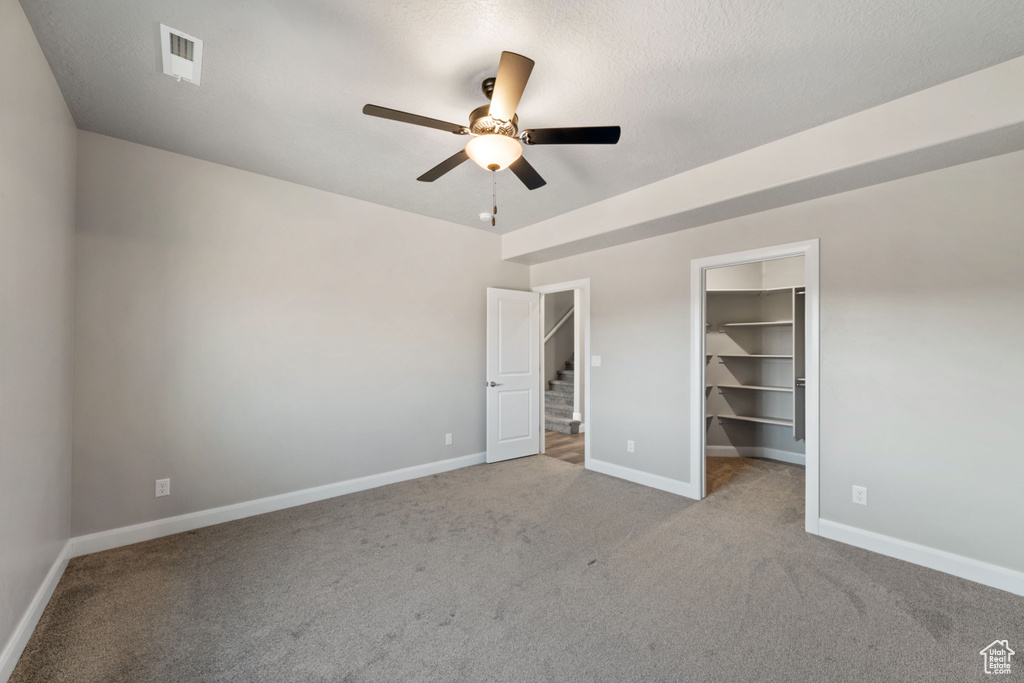Unfurnished bedroom featuring ceiling fan, a closet, light carpet, and a spacious closet