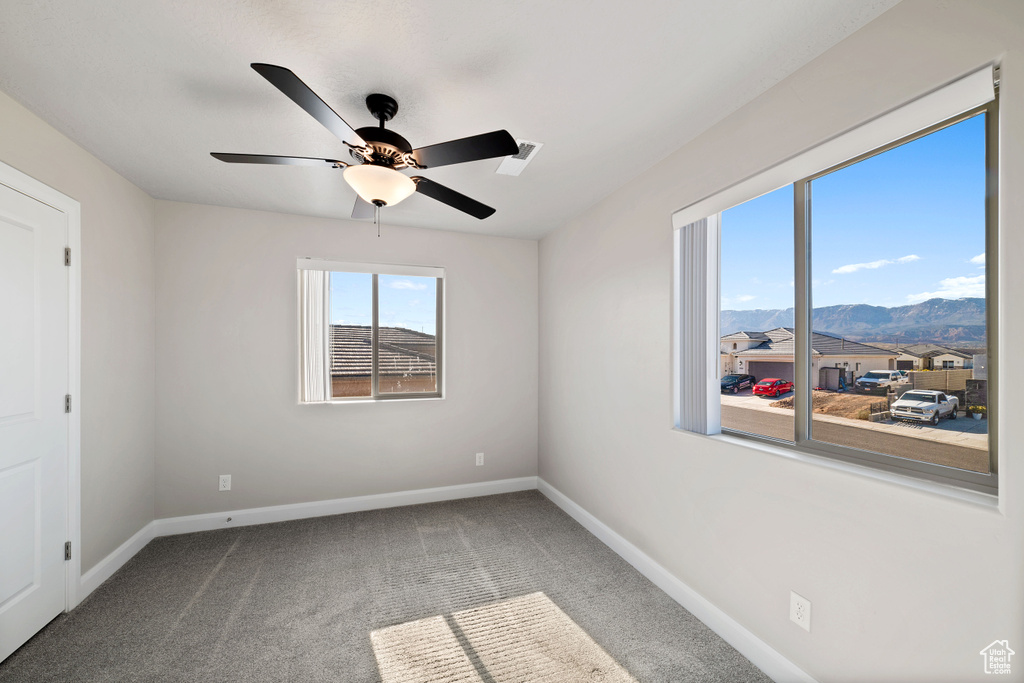 Unfurnished room featuring carpet flooring, ceiling fan, and a mountain view