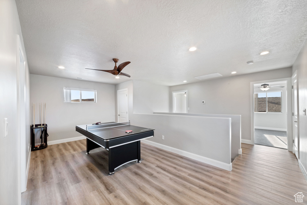 Game room featuring light hardwood / wood-style flooring, ceiling fan, and a textured ceiling