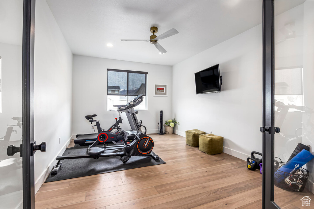 Workout area featuring ceiling fan, light wood-type flooring, and french doors