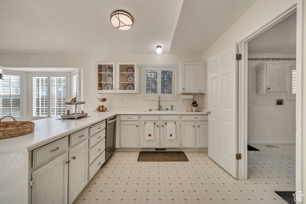 Kitchen with dishwasher, white cabinetry, sink, and light tile flooring