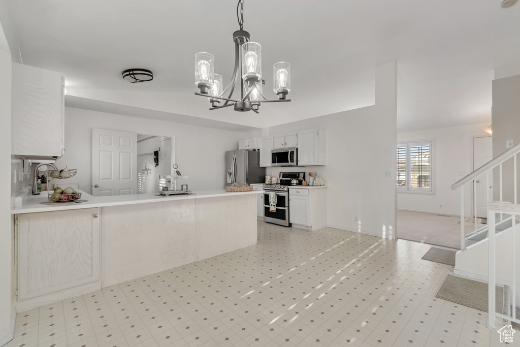 Kitchen featuring light tile floors, stainless steel appliances, a chandelier, pendant lighting, and white cabinetry