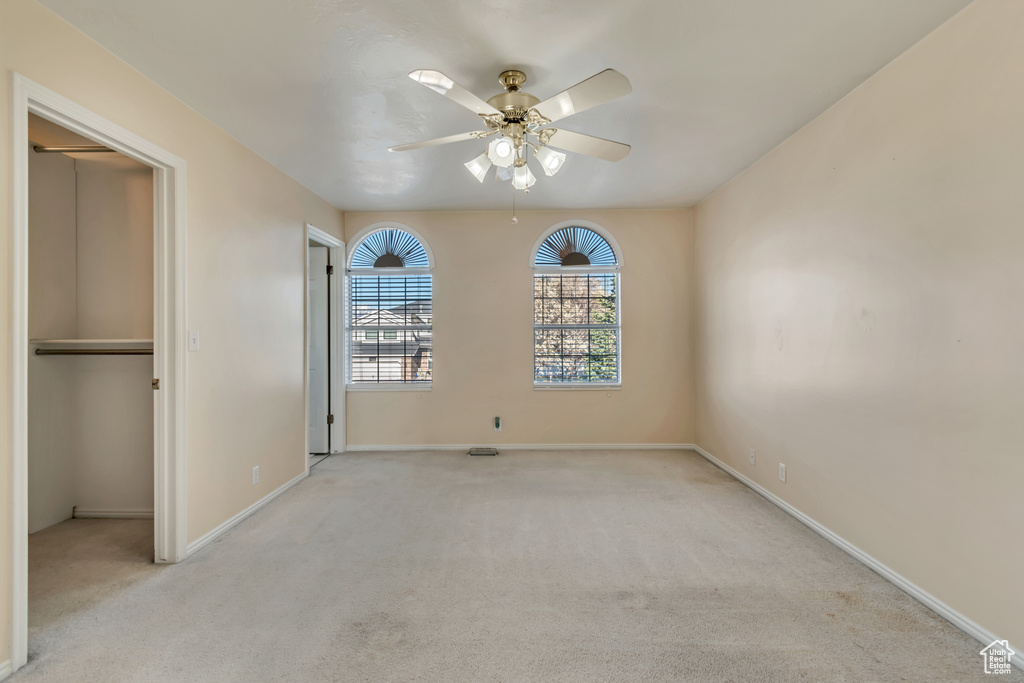 Unfurnished bedroom with ceiling fan, light colored carpet, and a closet