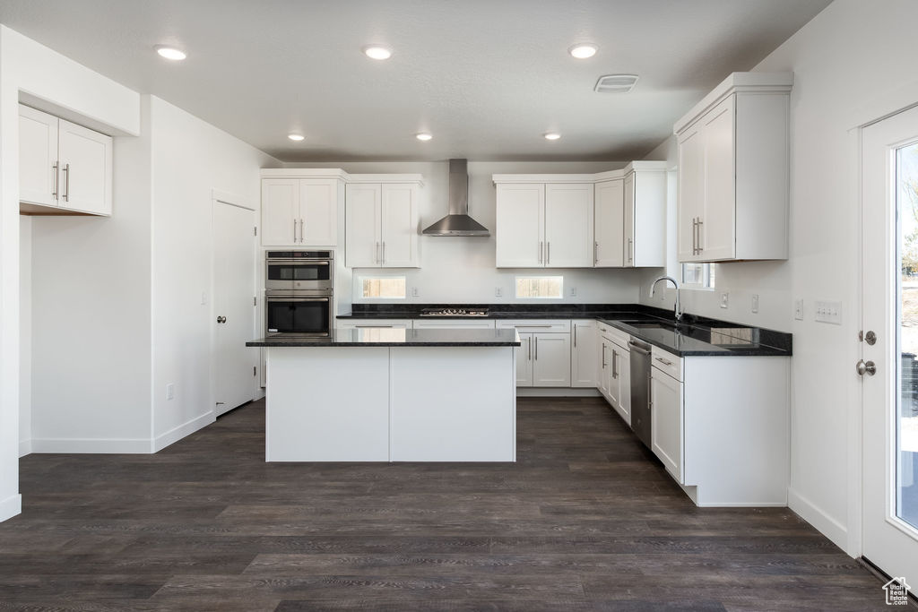 Kitchen featuring white cabinetry, dark hardwood / wood-style floors, a kitchen island, and wall chimney exhaust hood