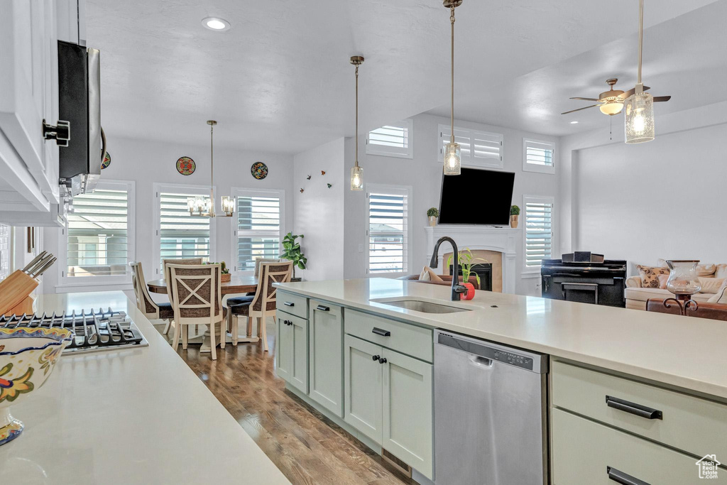 Kitchen with appliances with stainless steel finishes, sink, pendant lighting, light wood-type flooring, and ceiling fan with notable chandelier