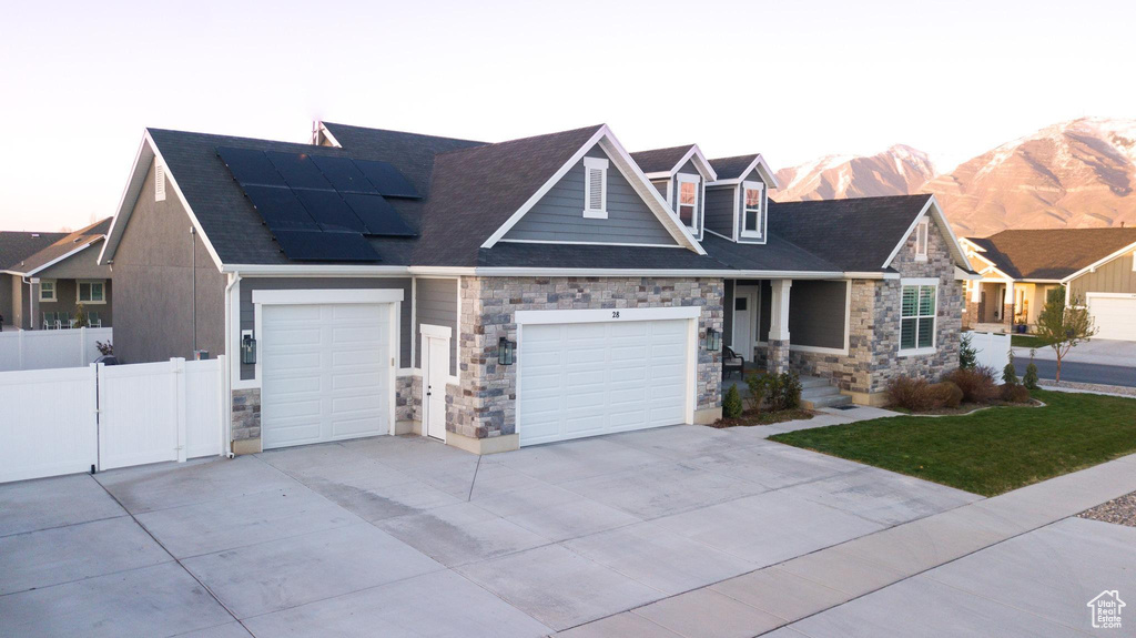 View of front of home with solar panels, a mountain view, and a garage