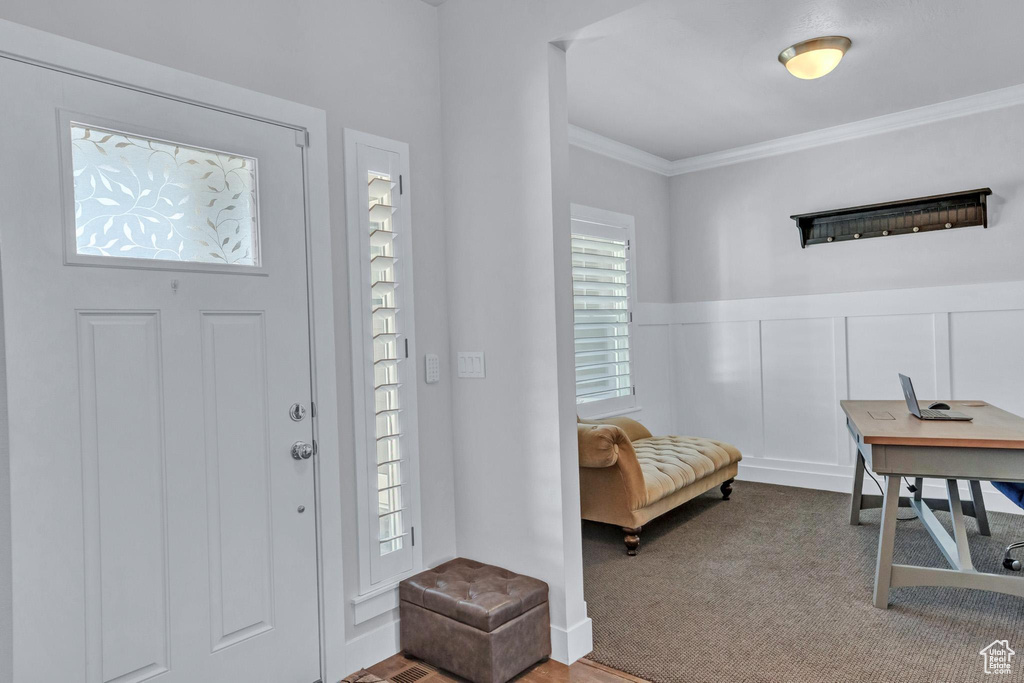 Entrance foyer with crown molding and carpet