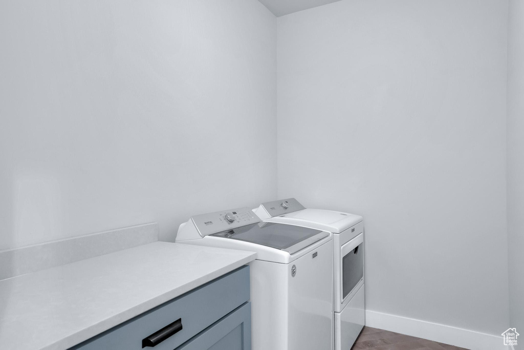 Laundry area featuring washing machine and clothes dryer, cabinets, and dark hardwood / wood-style floors