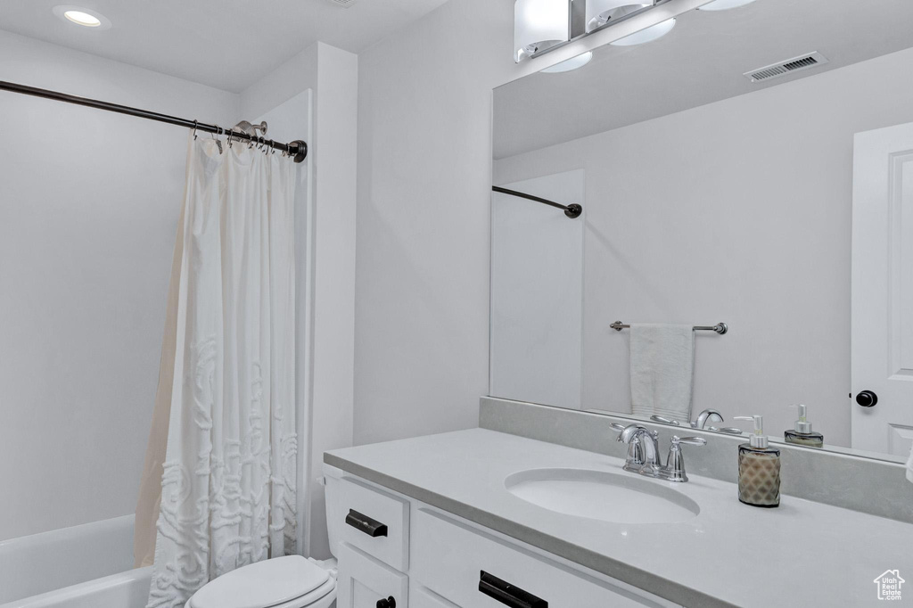 Full bathroom featuring shower / tub combo with curtain, toilet, and vanity with extensive cabinet space