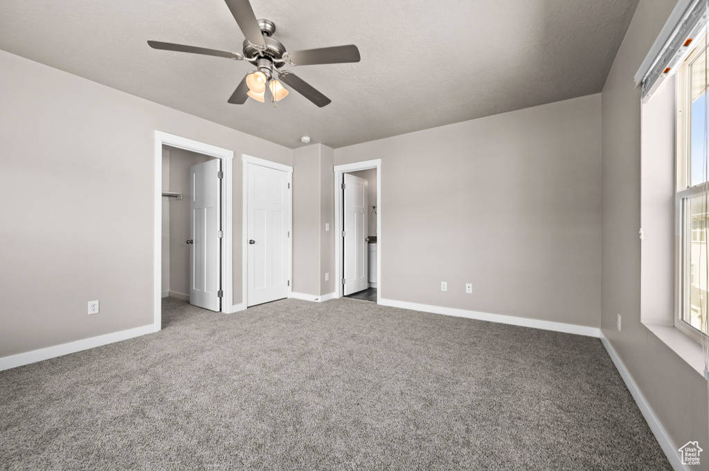 Unfurnished bedroom with light colored carpet, ceiling fan, and multiple windows