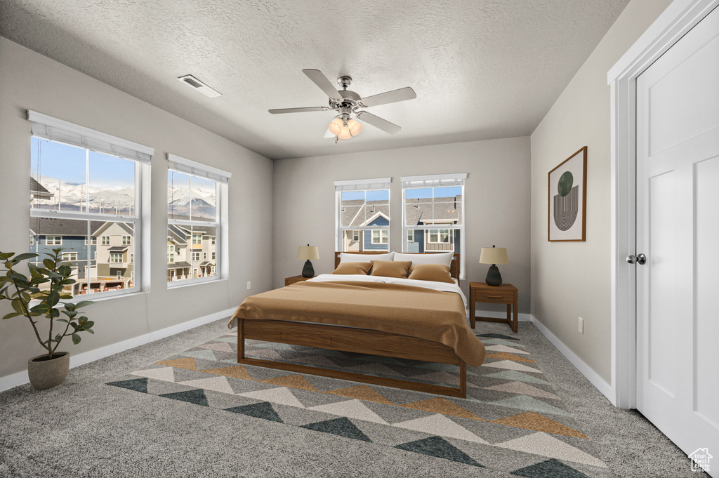 Bedroom with light colored carpet, ceiling fan, and a textured ceiling