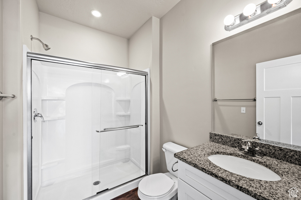 Bathroom featuring oversized vanity, toilet, and a shower with shower door